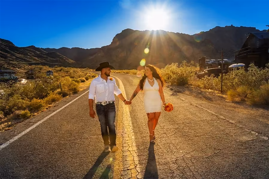 A wedding couple stands on the open road leading into Eldorado Canyon toward Nelson Ghost Town, Nevada